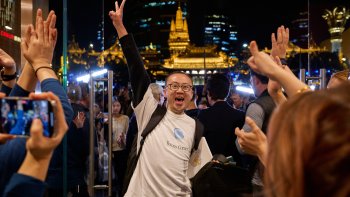Členové týmu vítají první zákazníky ve dveřích osmé prodejny Apple Jing'an v Šanghaji.