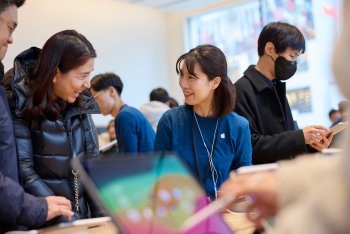 Člen týmu Apple Hongdae ukazuje zákazníkovi řadu iPadů.
