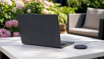 Klávesnice MacBooku vedle kulaté bezdrátové nabíjecí podložky